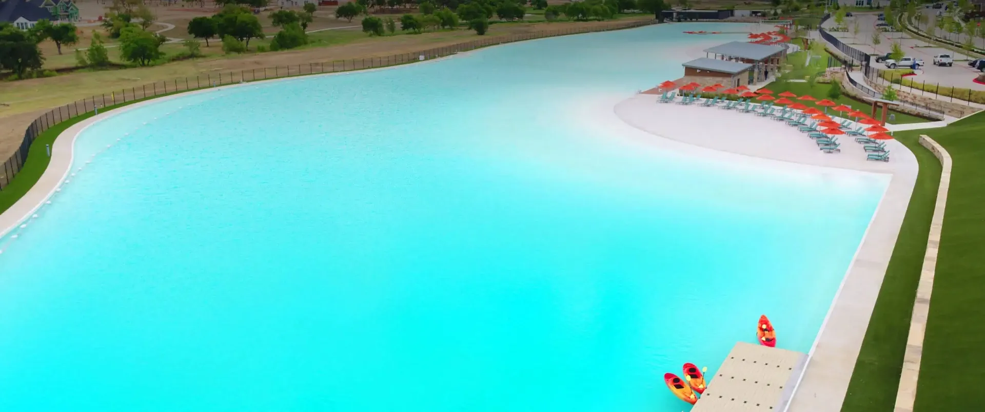 Aerial view of the Windsong Ranch Crystal Lagoon with sandy beach and surrounding homes